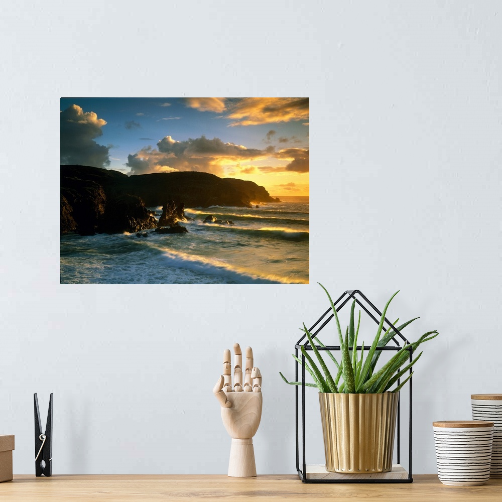 A bohemian room featuring Photograph of rock cliffs in ocean with waves rolling in under a cloudy sky at sunrise.