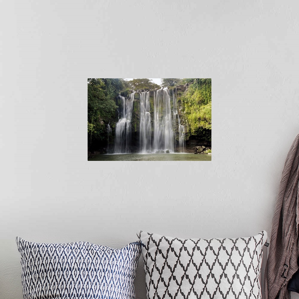 A bohemian room featuring Long exposure photograph of a waterfall over a rocky cliff in Central America with leafy jungle v...