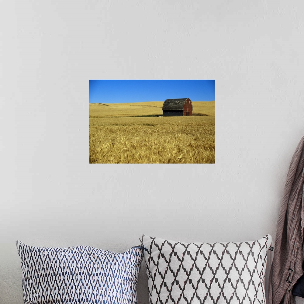 A bohemian room featuring Large wall art of a barn in the middle of a field printed on canvas.