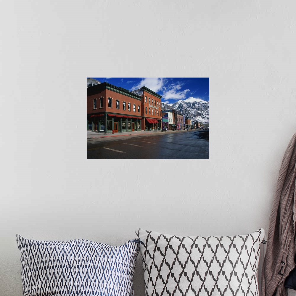 A bohemian room featuring Photograph of street corner lined with buildings and shops with snow covered mountains in the bac...