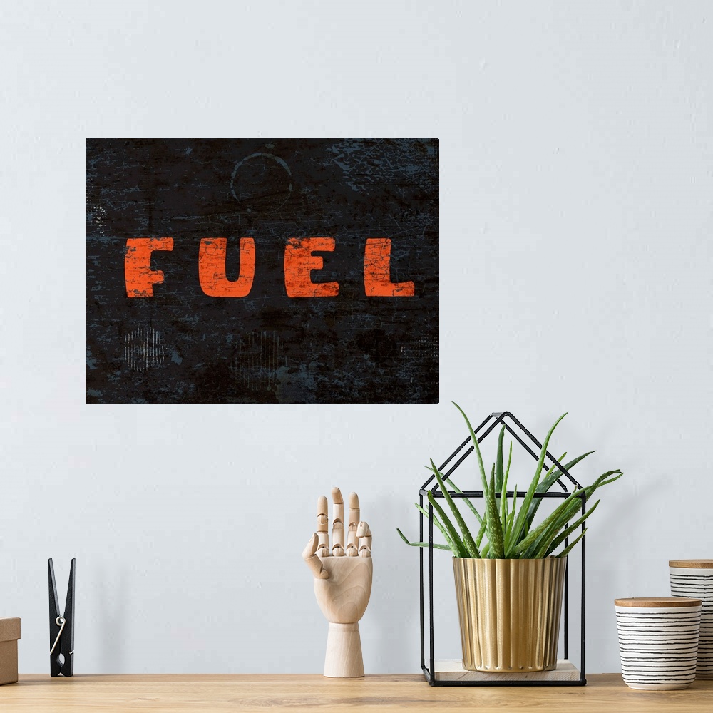 A bohemian room featuring Graphic rusty wall art of distressed typography with the the word FUEL large, in orange, and in c...