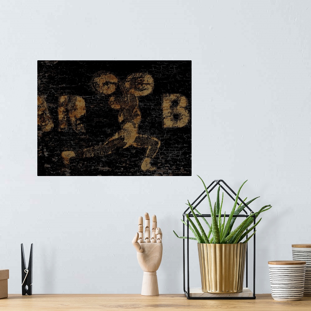 A bohemian room featuring Distressed vintage wall art of a gold image of a weightlifter with barbell overhead on a black ba...
