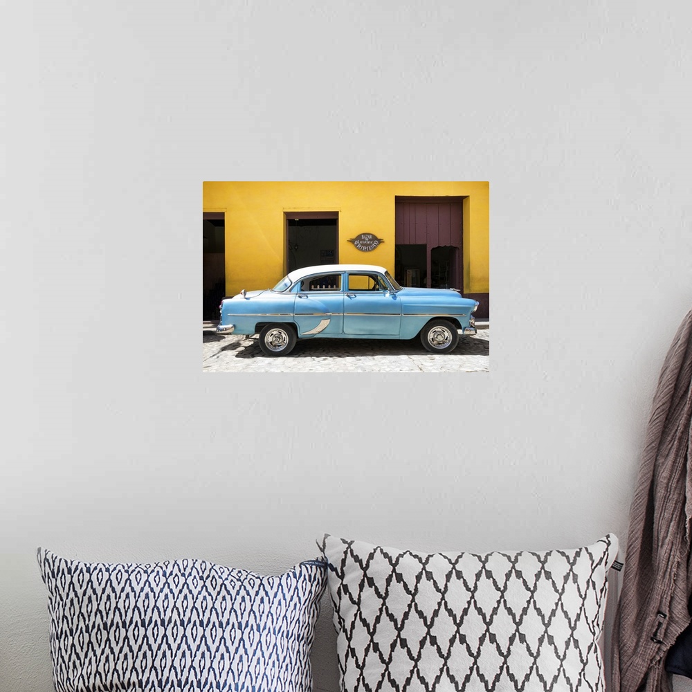 A bohemian room featuring Photograph of a blue vintage car parked in front of a bright yellow building on a cobblestone road.