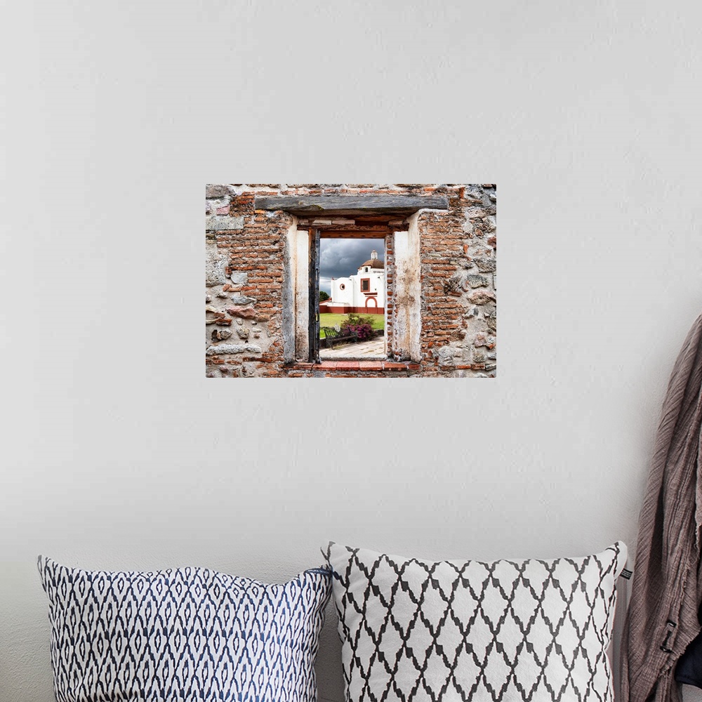 A bohemian room featuring View of a red and white church in Mexico framed through a stony, brick window. From the Viva Mexi...