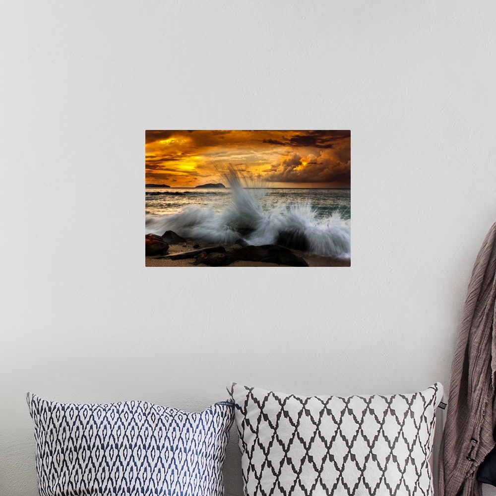 A bohemian room featuring Waves crashing on the rocky shore at sunset.