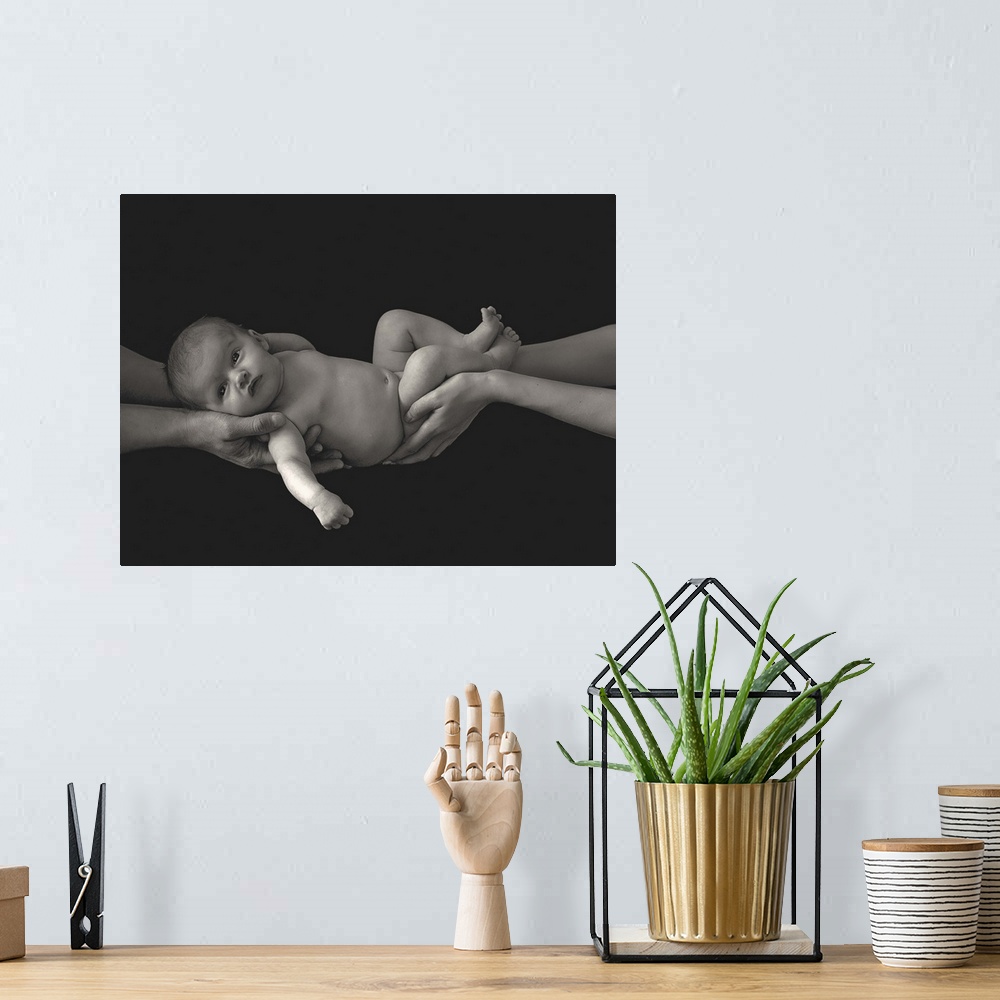 A bohemian room featuring A couple holding a newborn baby in their hands.