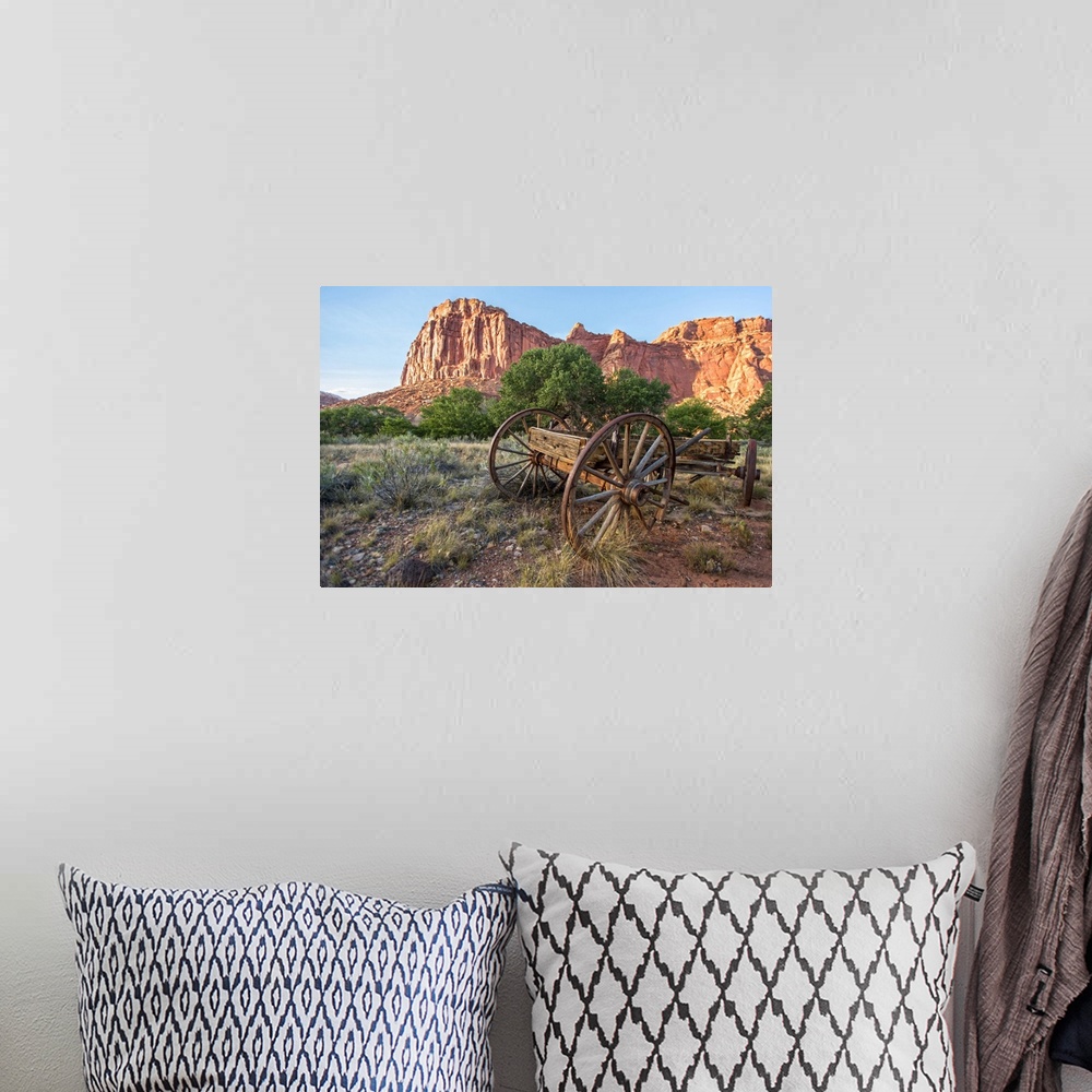 A bohemian room featuring An antique wagon under Fruita's rock formations in Capitol Reef National Park, Utah.