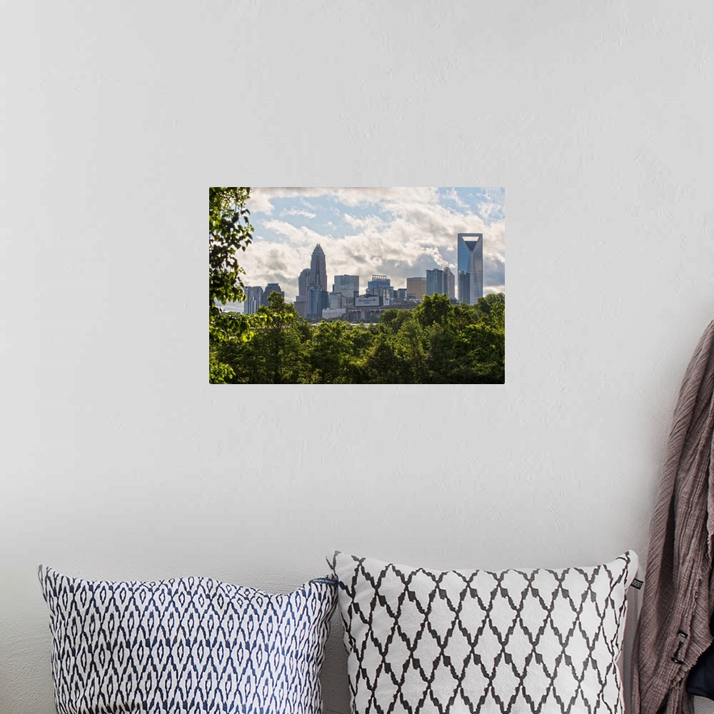 A bohemian room featuring A forest of trees in the foreground of the Charlotte North Carolina city skyline.