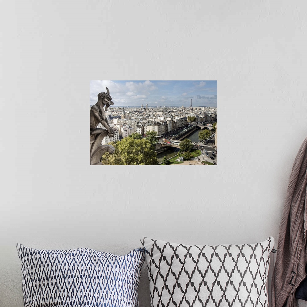A bohemian room featuring Photograph of a gargoyle statue watching over the city of Paris.