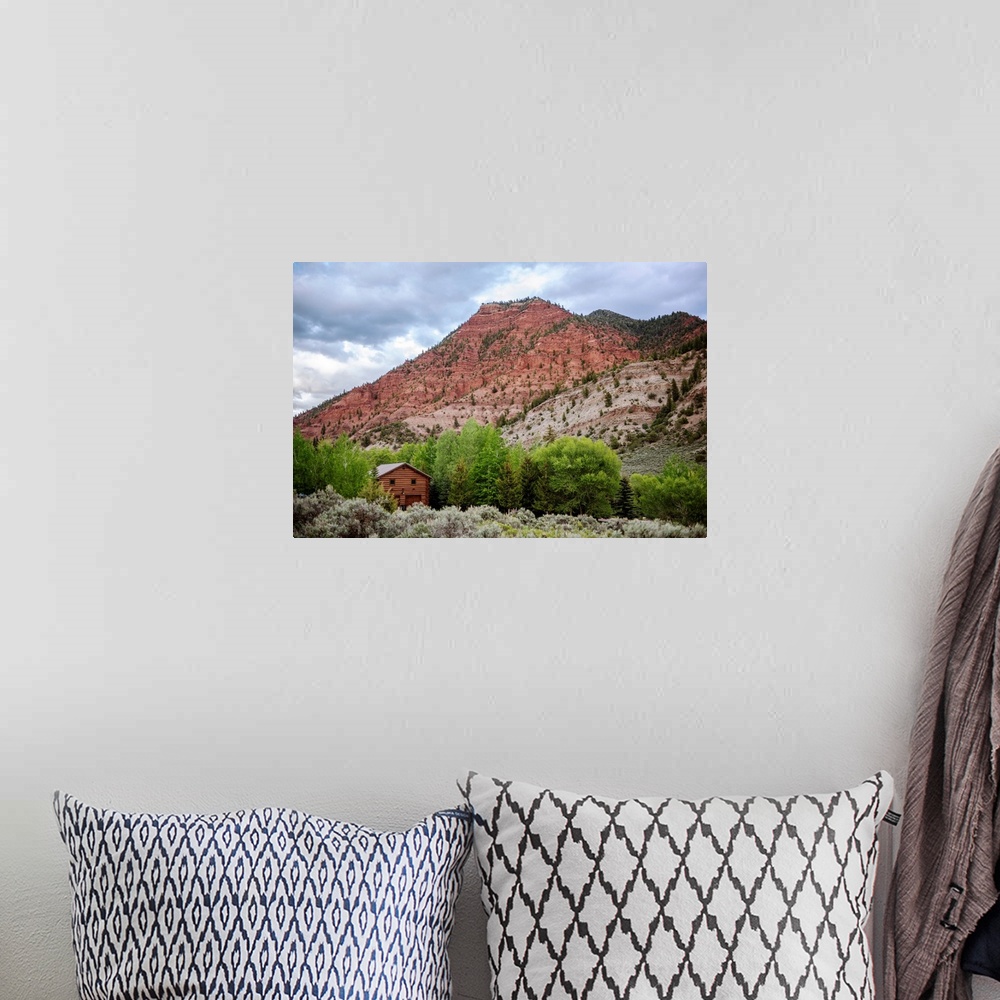 A bohemian room featuring Photo of a wood cabin nestled with trees under a mountain cliffside in Colorado.