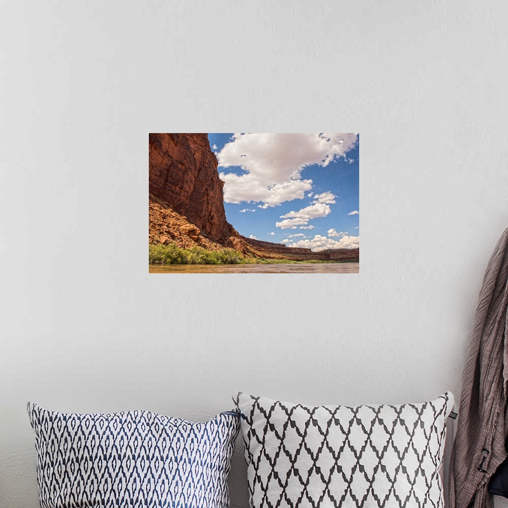 A bohemian room featuring Tall sandstone cliffs tower along the edge of the Colorado River, with clouds and blue skies over...