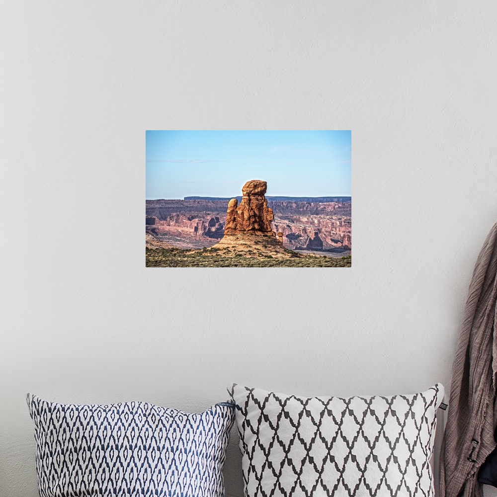 A bohemian room featuring Sandstone tower overlooking the canyon and desert under a pale blue sky in Arches National Park, ...