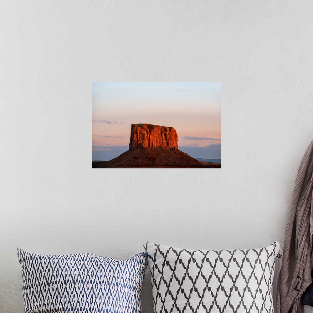 A bohemian room featuring The sun sets on Mitchell Butte, highlighting the rich red sandstone In Monument Valley, Arizona.
