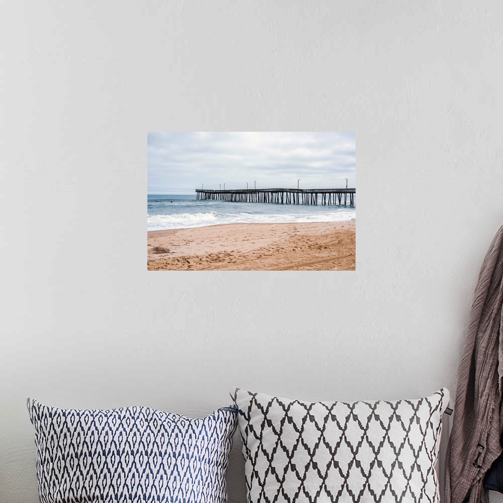 A bohemian room featuring A fishing pier reaches out to the Atlantic ocean while waves crash onto Virginia's sandy beach.