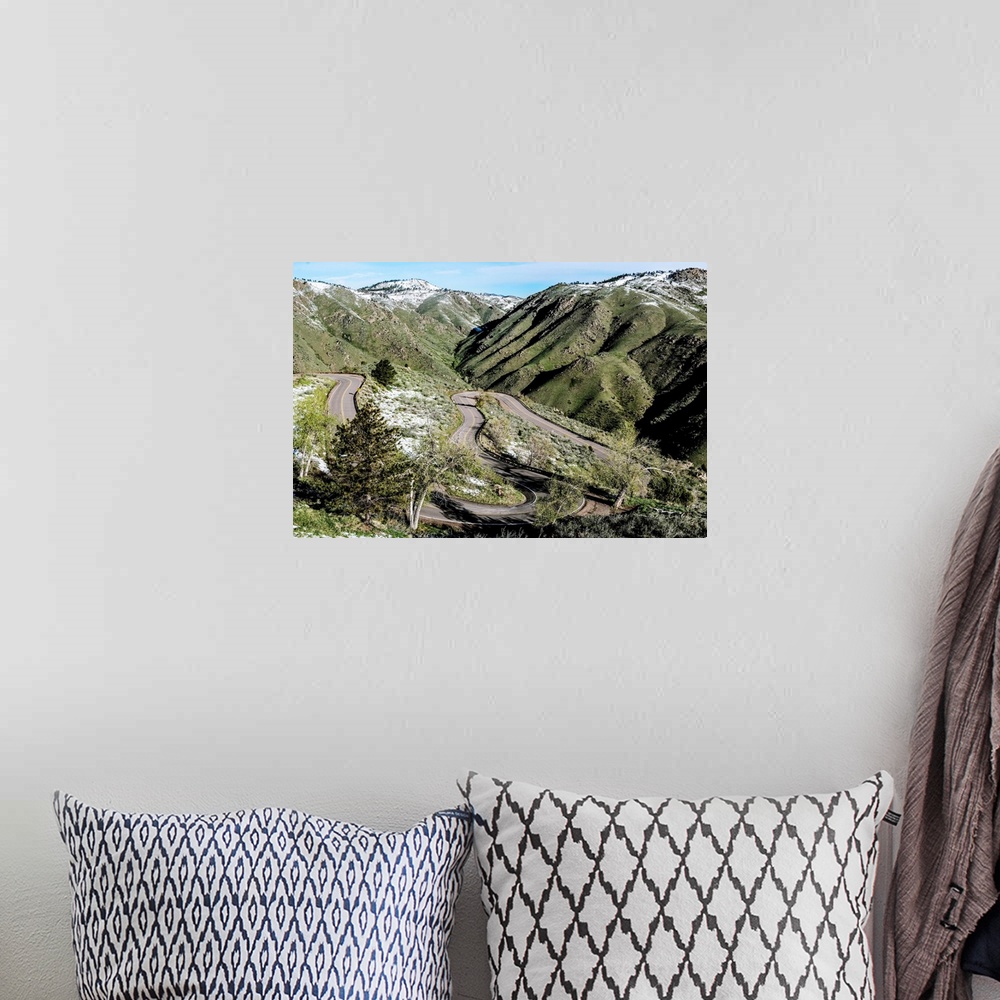 A bohemian room featuring Photo of a winding road below a mountain slightly covered in snow in Colorado.