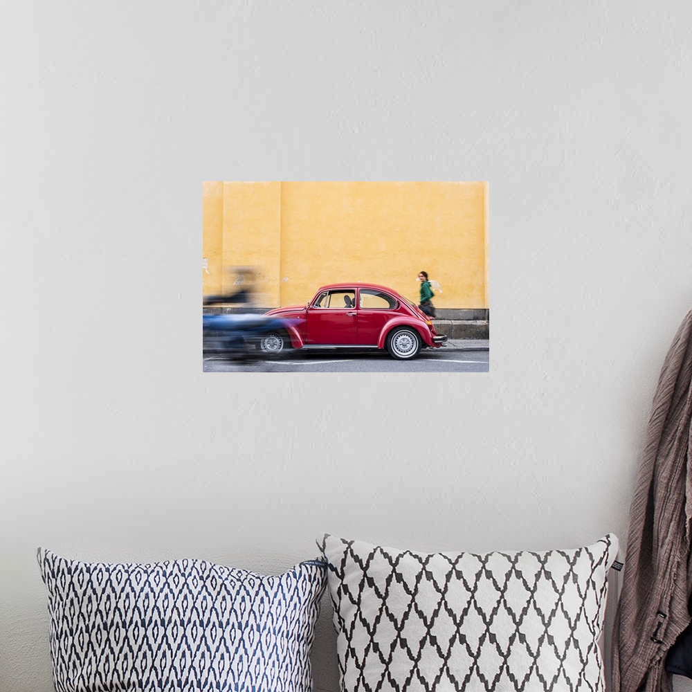 A bohemian room featuring A woman walking past a red VW Beetle in the colourful streets of Popayan, Colombia, South America