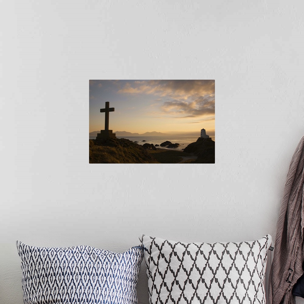 A bohemian room featuring Stone Cross and old lighthouse in silhouette at sunset, Anglesey, North Wales, UK