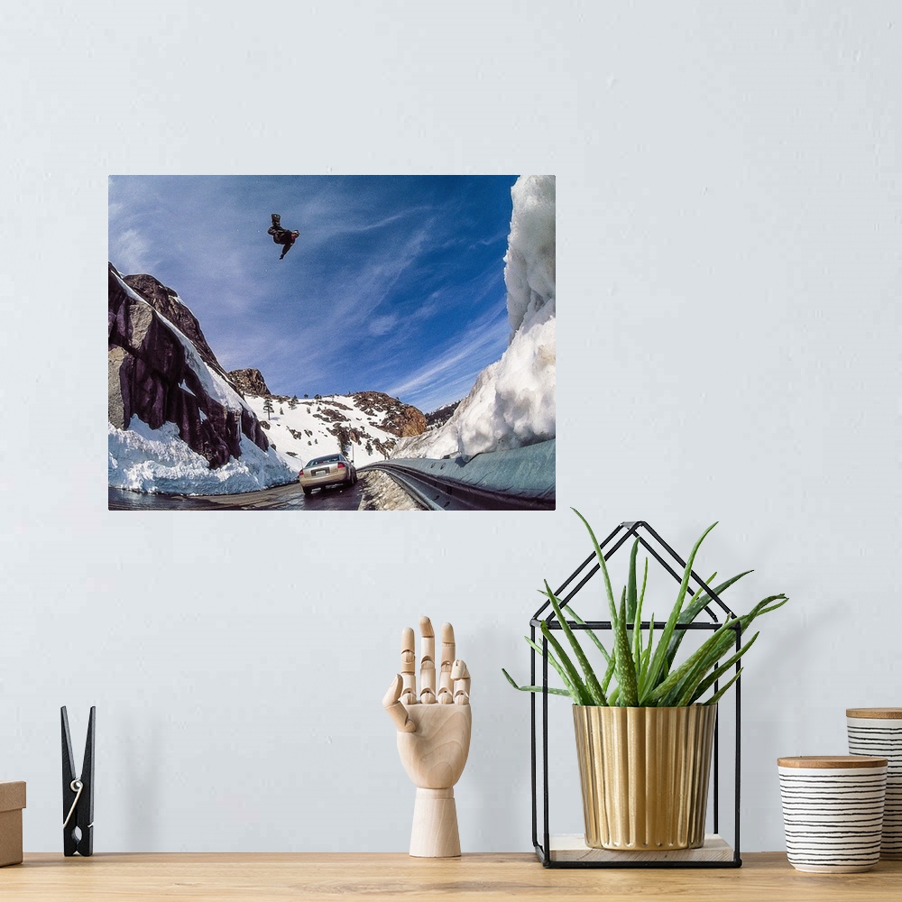 A bohemian room featuring Nate Mott flying on his snowboard over the Donner Summit, as a car passes by below, California, m...