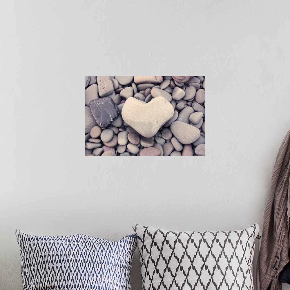 A bohemian room featuring A smooth stone in the shape of a heart on a bed of round pebbles.