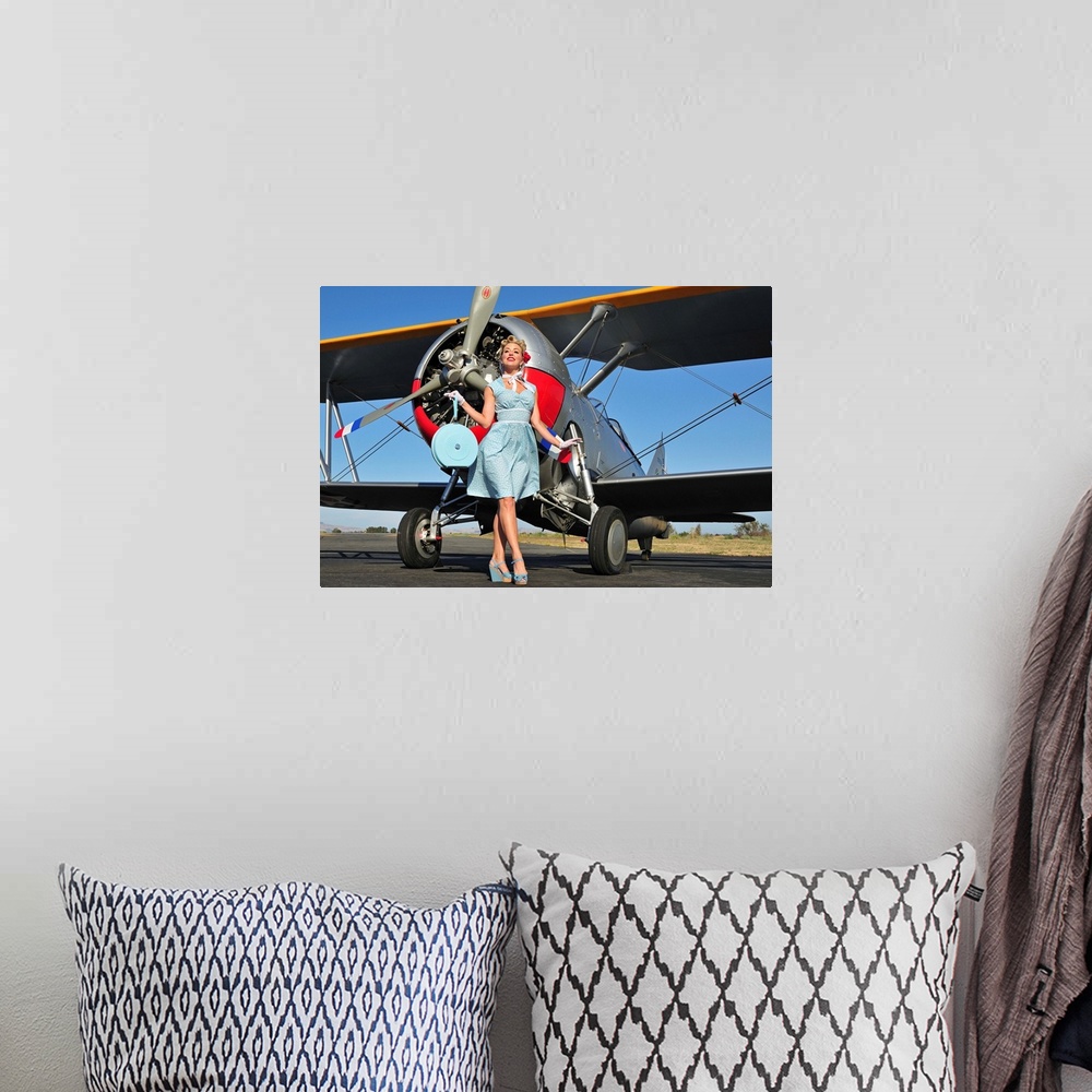 A bohemian room featuring Elegant 1940's style pin-up girl standing in front of an F3F biplane.