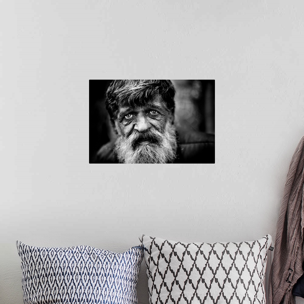 A bohemian room featuring Close up of a mans face with a grey beard and tired eyes