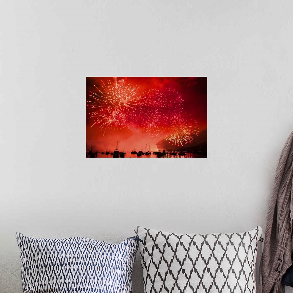 A bohemian room featuring Fireworks and boats in the ocean against a red sky