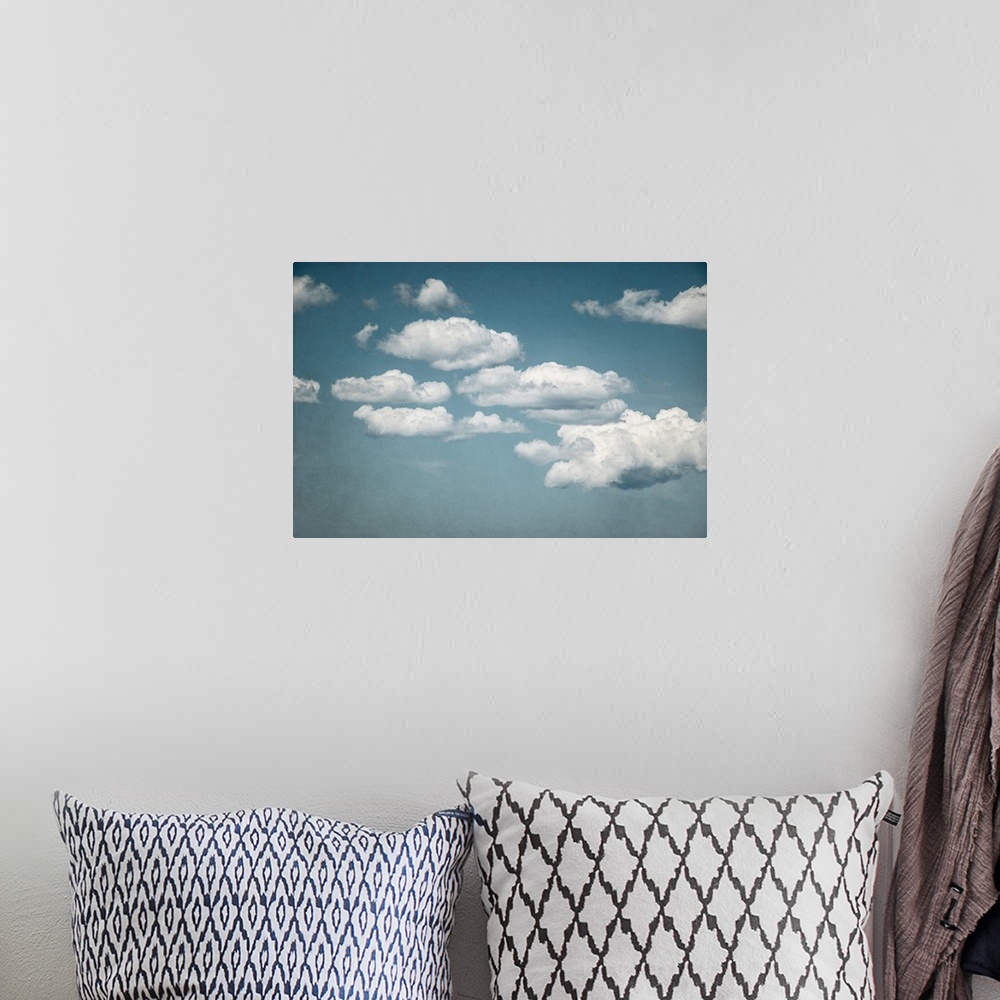 A bohemian room featuring A contemporary photograph of fluffy white clouds against a pale blue sky.