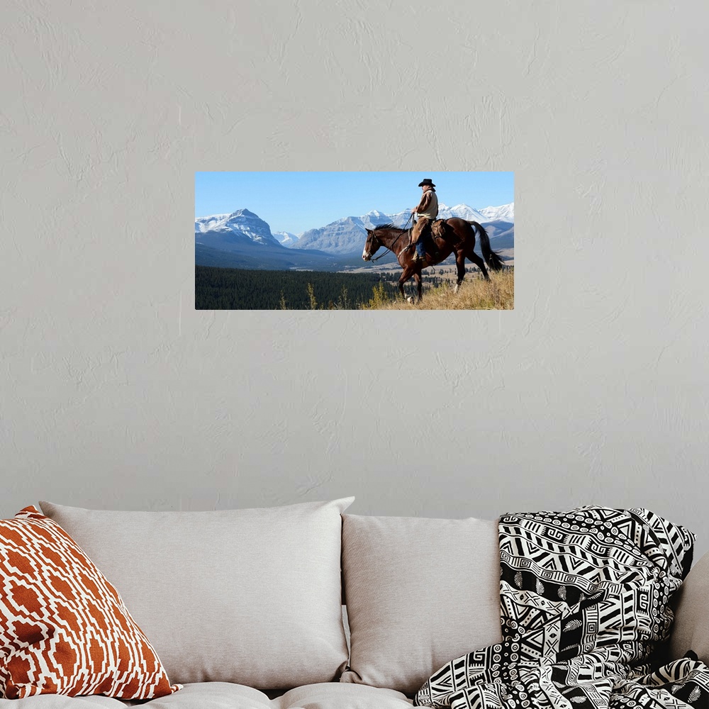 A bohemian room featuring Cowboy riding with a view of the Rocky mountains, Ya-Ha-Tinda Ranch, Clearwater County, Alberta, ...