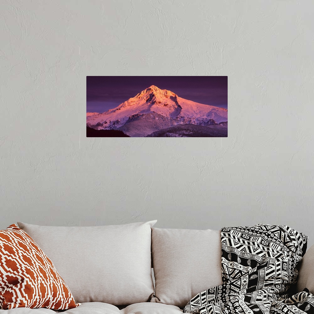 A bohemian room featuring Mount Hood illuminated in sunset colors at dusk.