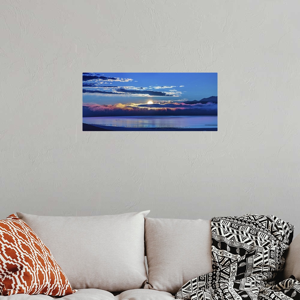 A bohemian room featuring The sun peeking behind the clouds at dawn over Mono Lake, California.