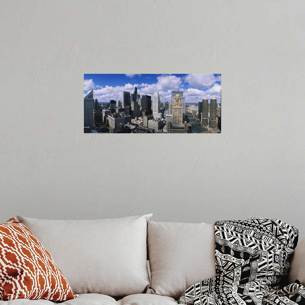 A bohemian room featuring Puffy white clouds over a wide array of skyscrapers in the industrious Midwestern city.