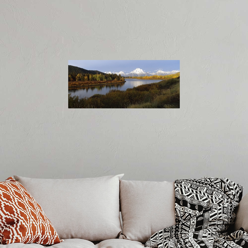 A bohemian room featuring A landscape photograph of a river winding through the meadowlands with snow covered mountain peak...