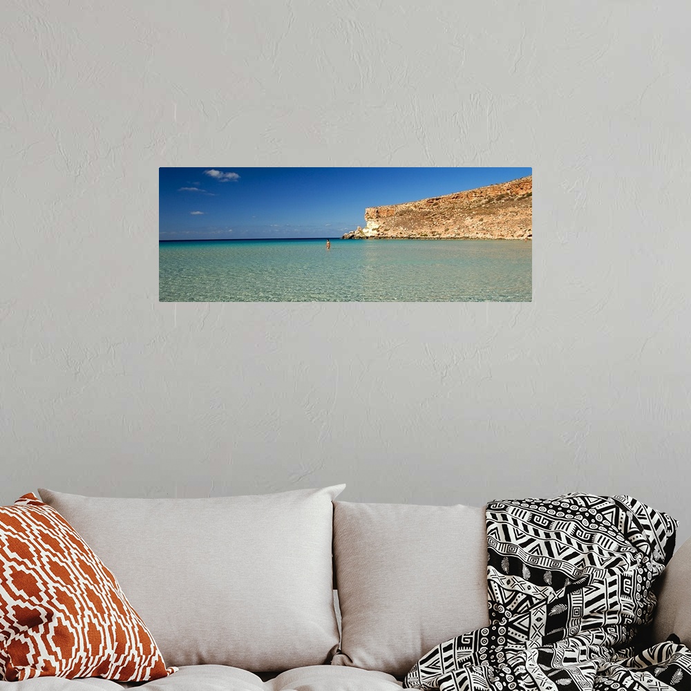 A bohemian room featuring Tourist walking in the sea, Spiaggia Dei Conigli, Italy