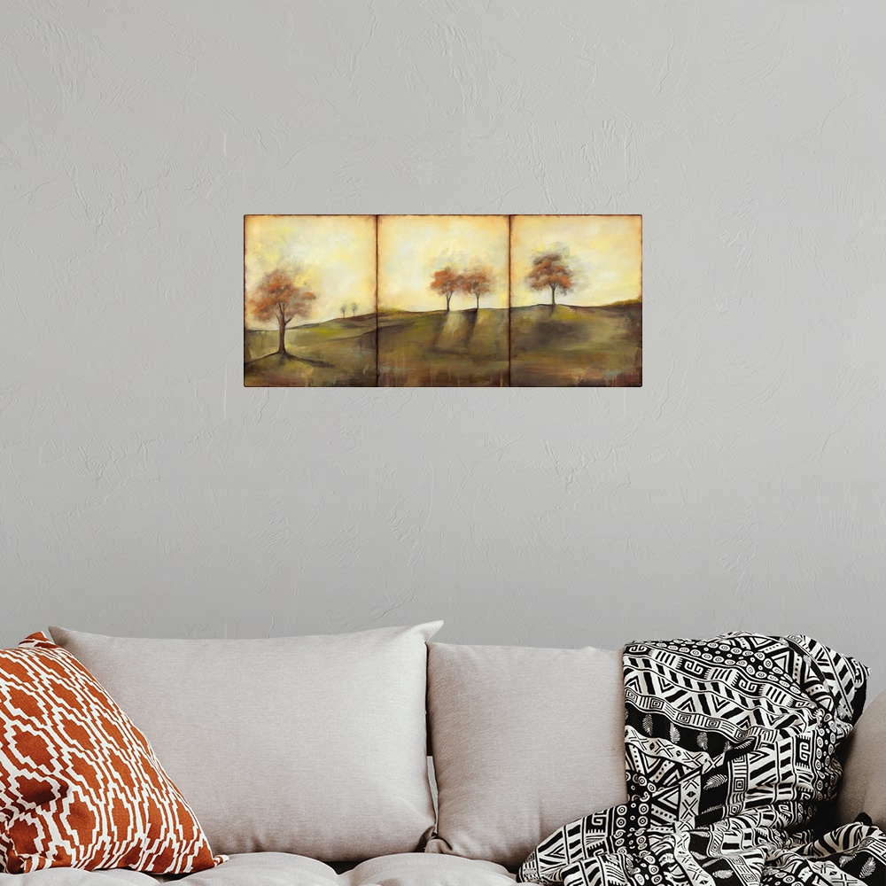 A bohemian room featuring Triptych painting of a countryside meadow in the fall, with small groups of trees.