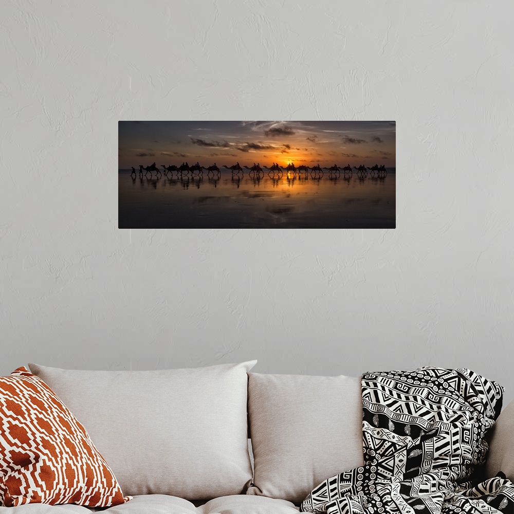 A bohemian room featuring Panoramic photograph of a line of camels walking through the desert at sunset.