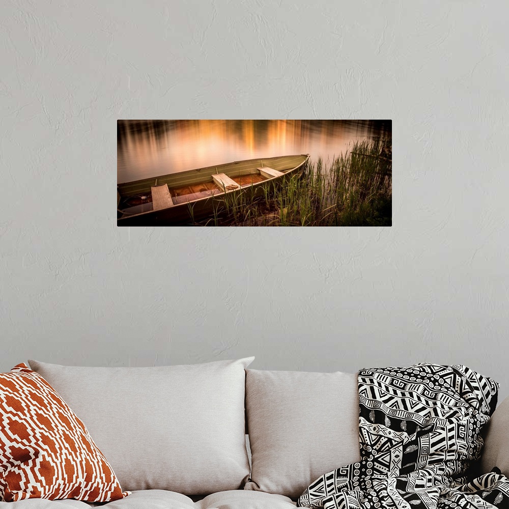 A bohemian room featuring A photograph of a rowboat siting still in the water.