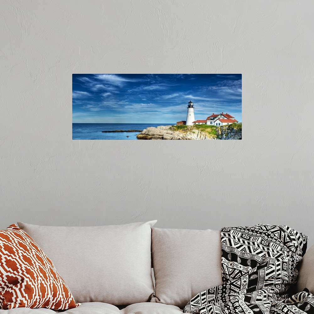 A bohemian room featuring Photograph of a lighthouse on the rocky shore against a blue sky.
