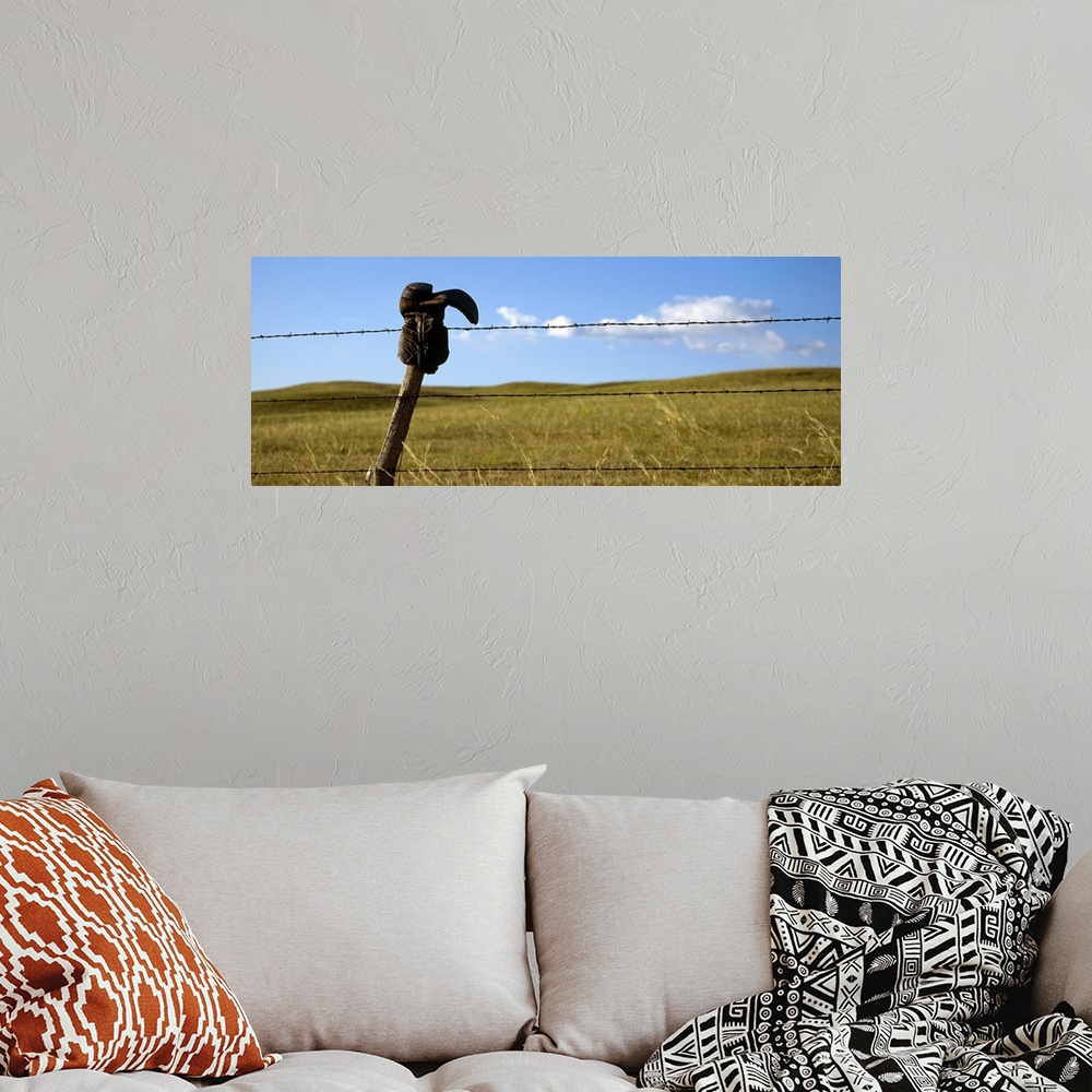 A bohemian room featuring Panoramic photograph of cowboy boot hanging upside down on a cable fence with grass covered hills...