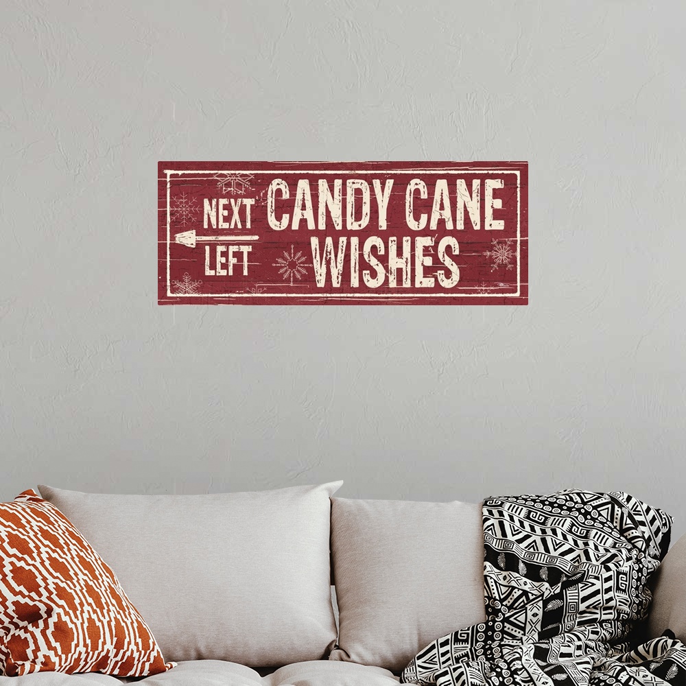 A bohemian room featuring Decorative artwork with a holiday theme with the text "Next Left Candy Cane Wishes" on a red back...