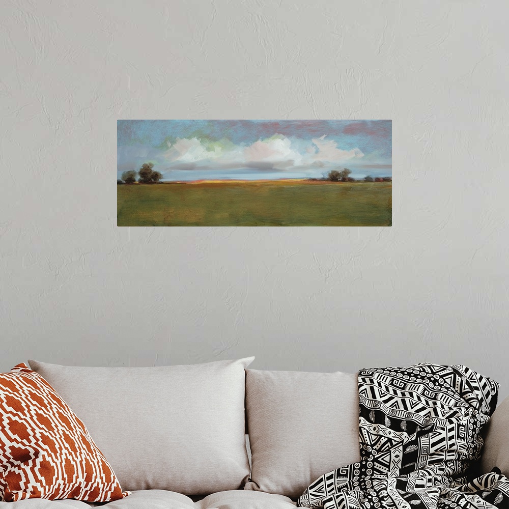A bohemian room featuring Contemporary landscape artwork of an open field with sparse trees under a cloudy sky.