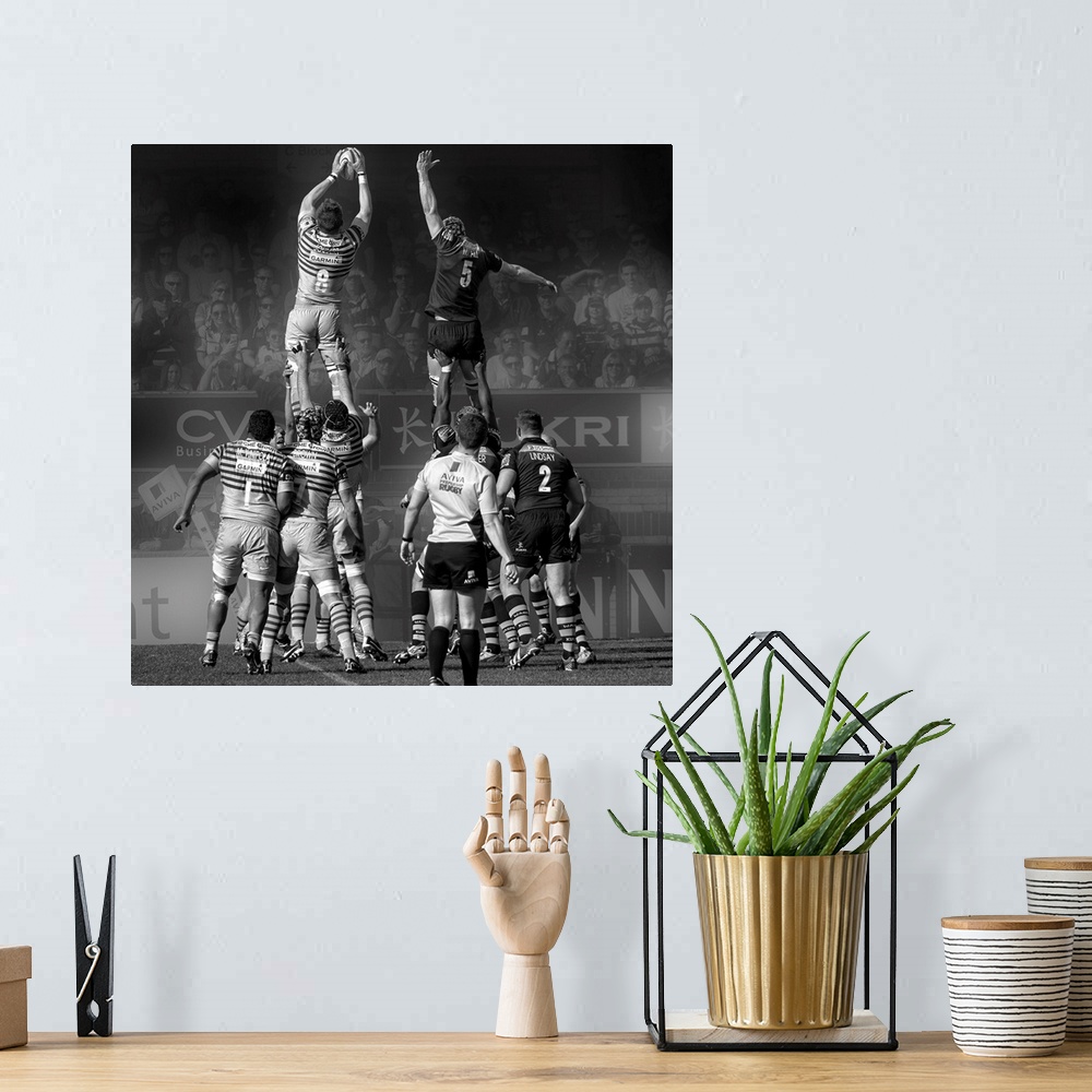 A bohemian room featuring A black and white photograph of rugby players in a match reaching into air to grasp the ball.