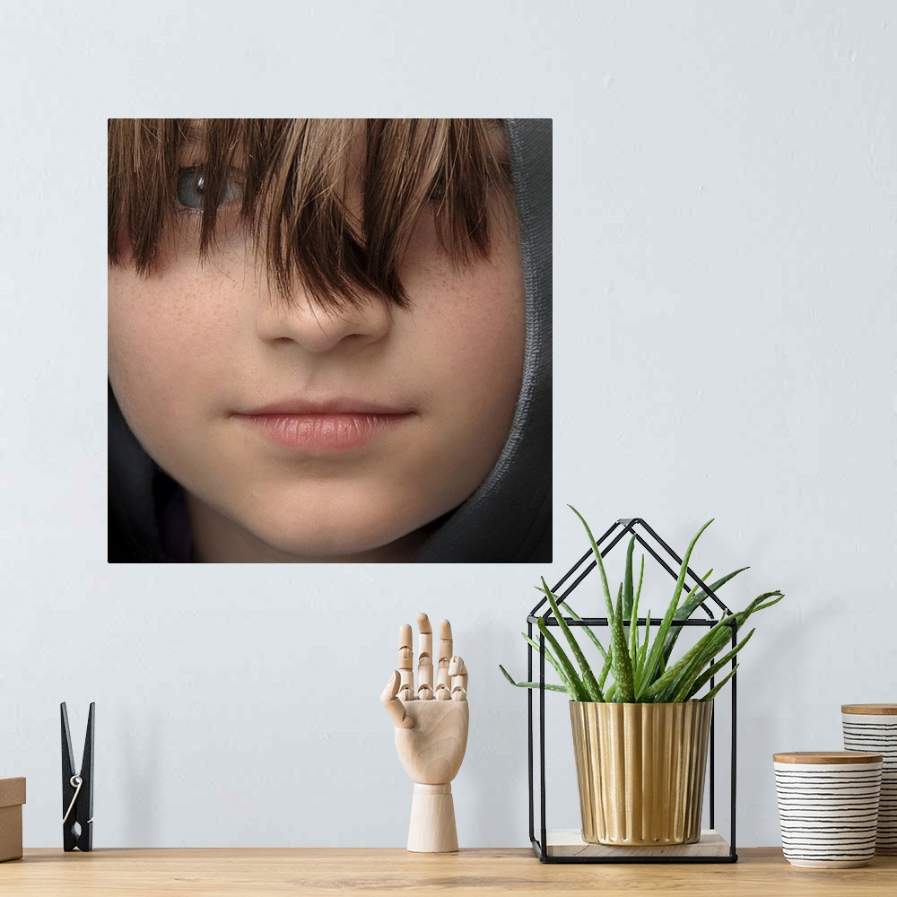 A bohemian room featuring Close-up portrait of a young boy with long bangs covering his eyes.