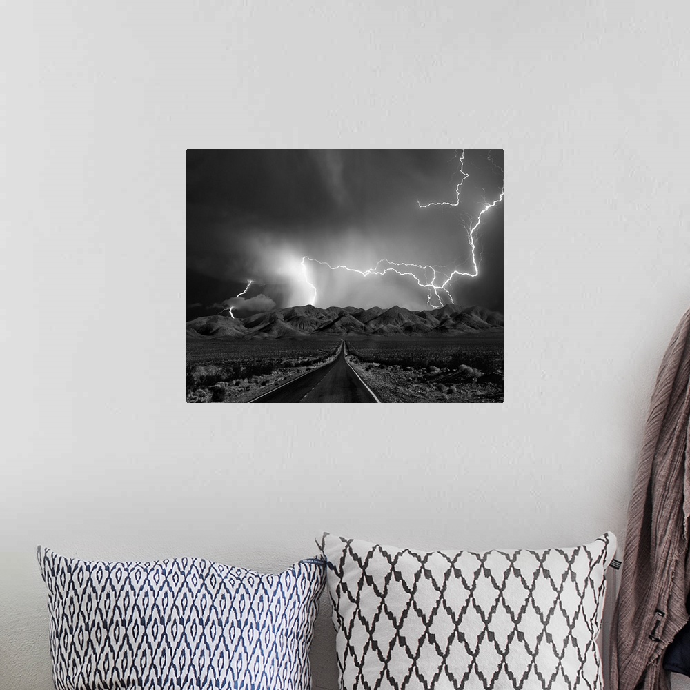 A bohemian room featuring A road leads to mountains in Nevada as lightning bolts shoot across the sky during  a thunderstorm.