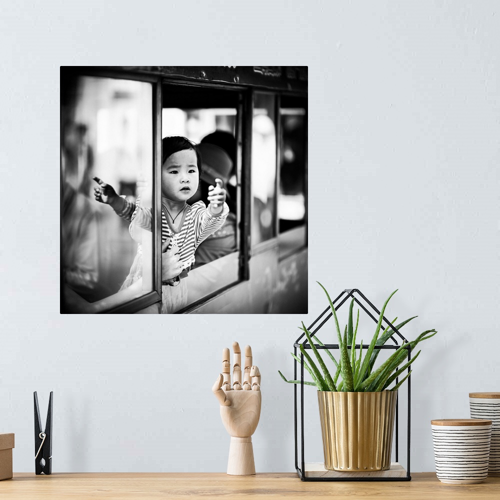 A bohemian room featuring A child reaches out from the window of a train as their parent holds them back.