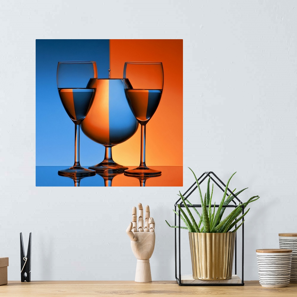A bohemian room featuring Conceptual image of three glasses reflecting mirror images of a blue and orange background.