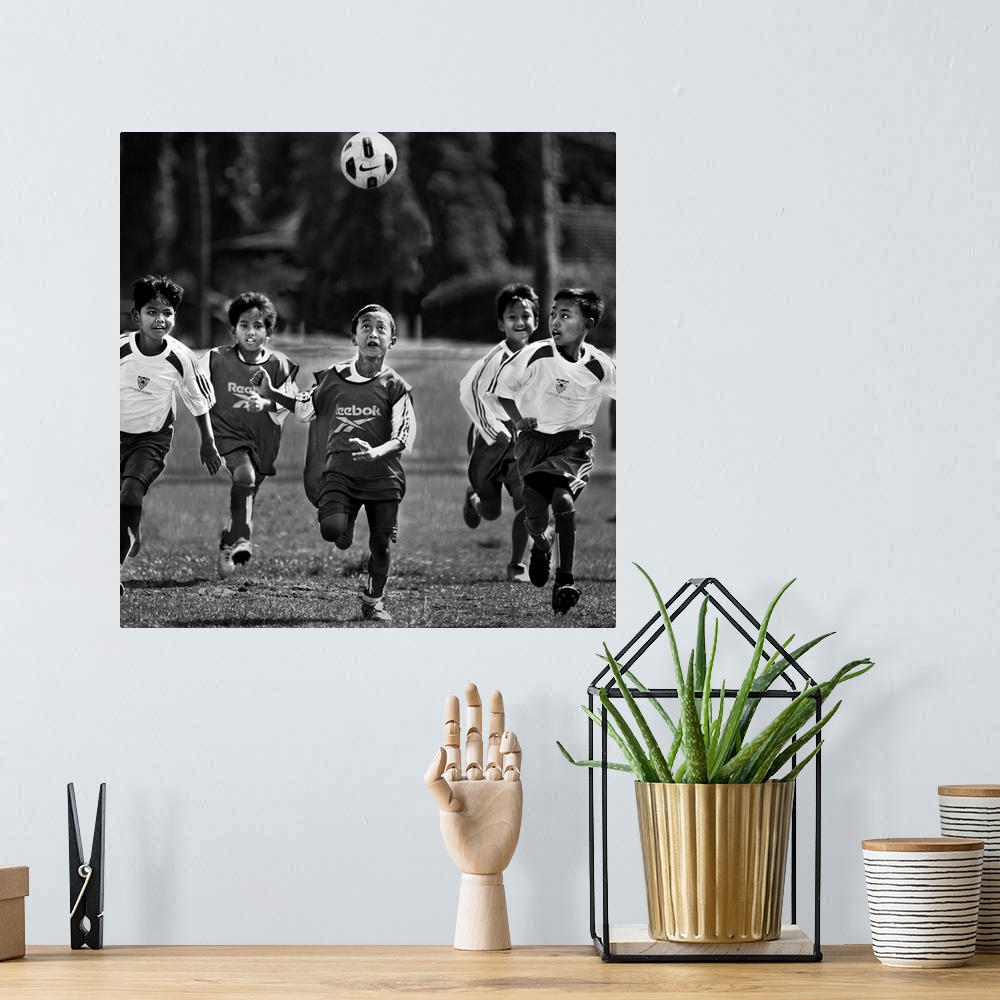 A bohemian room featuring A group of young boys playing soccer in a field, with the ball in the air.