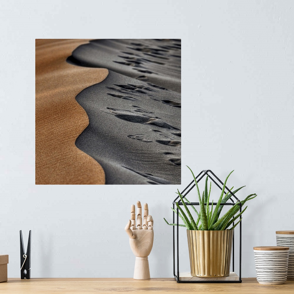 A bohemian room featuring Two opposing sides of a sand dune, one smooth and orange, the other grey and full of footprints.
