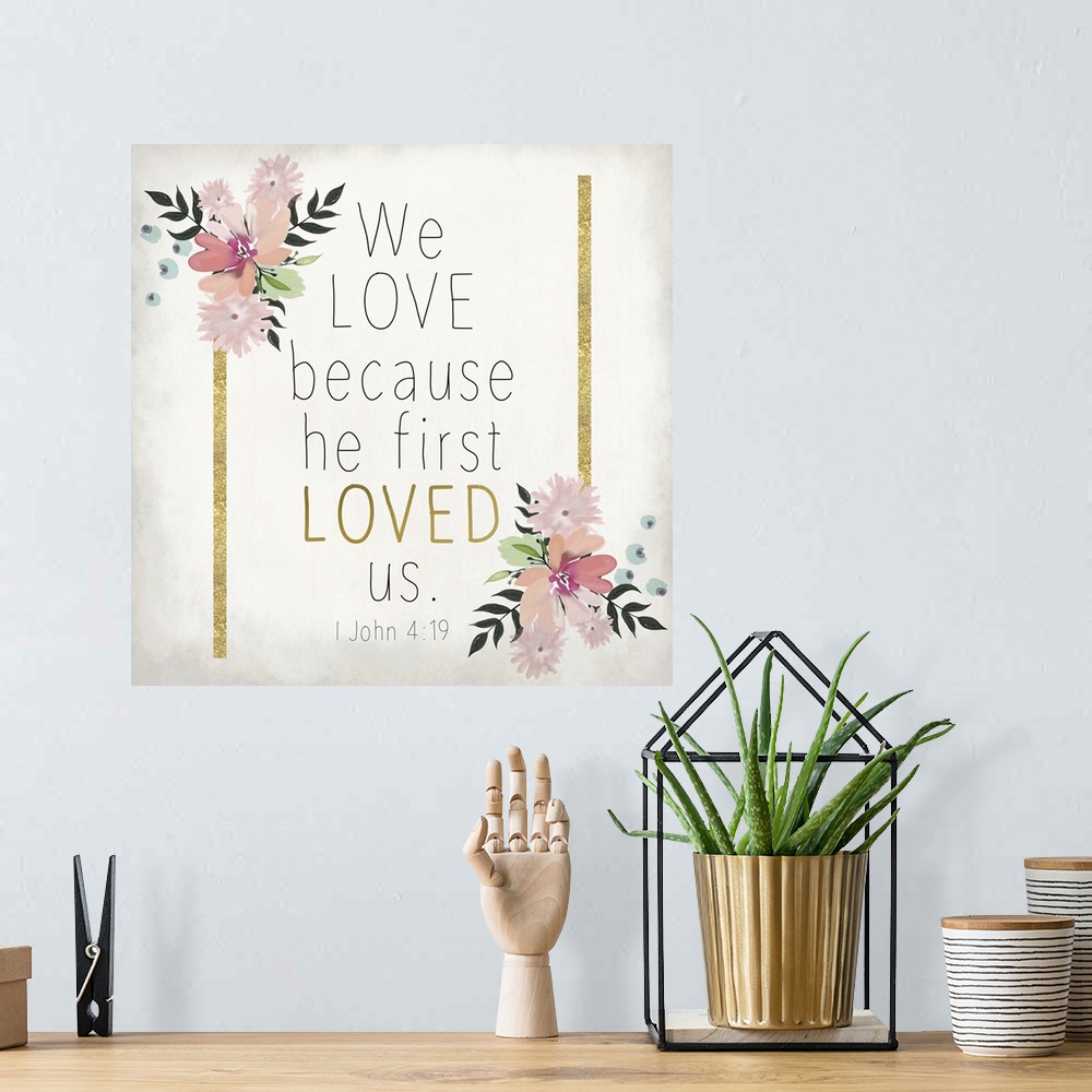 A bohemian room featuring Bible verse 1 John 4:19 with gold stripes and pink flowers.
