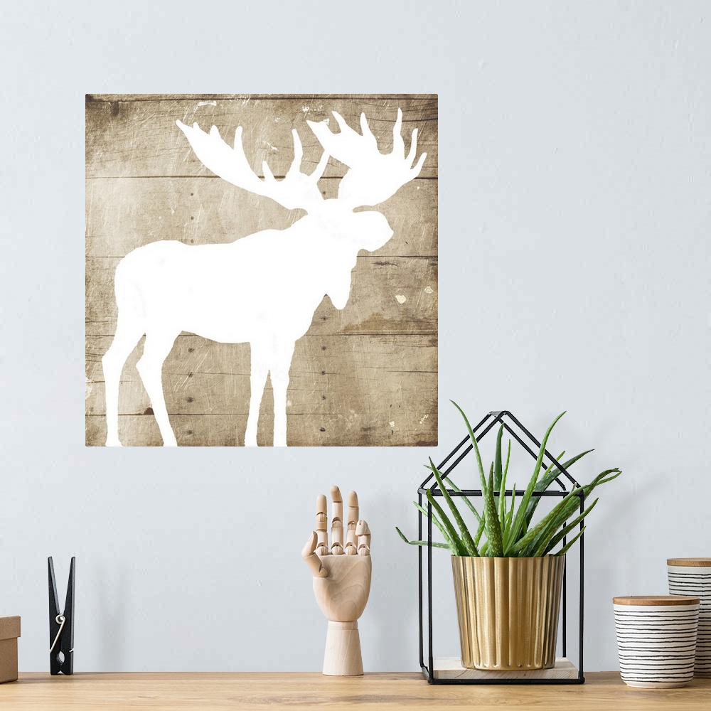 A bohemian room featuring A white silhouette of a moose painted on a wood background.