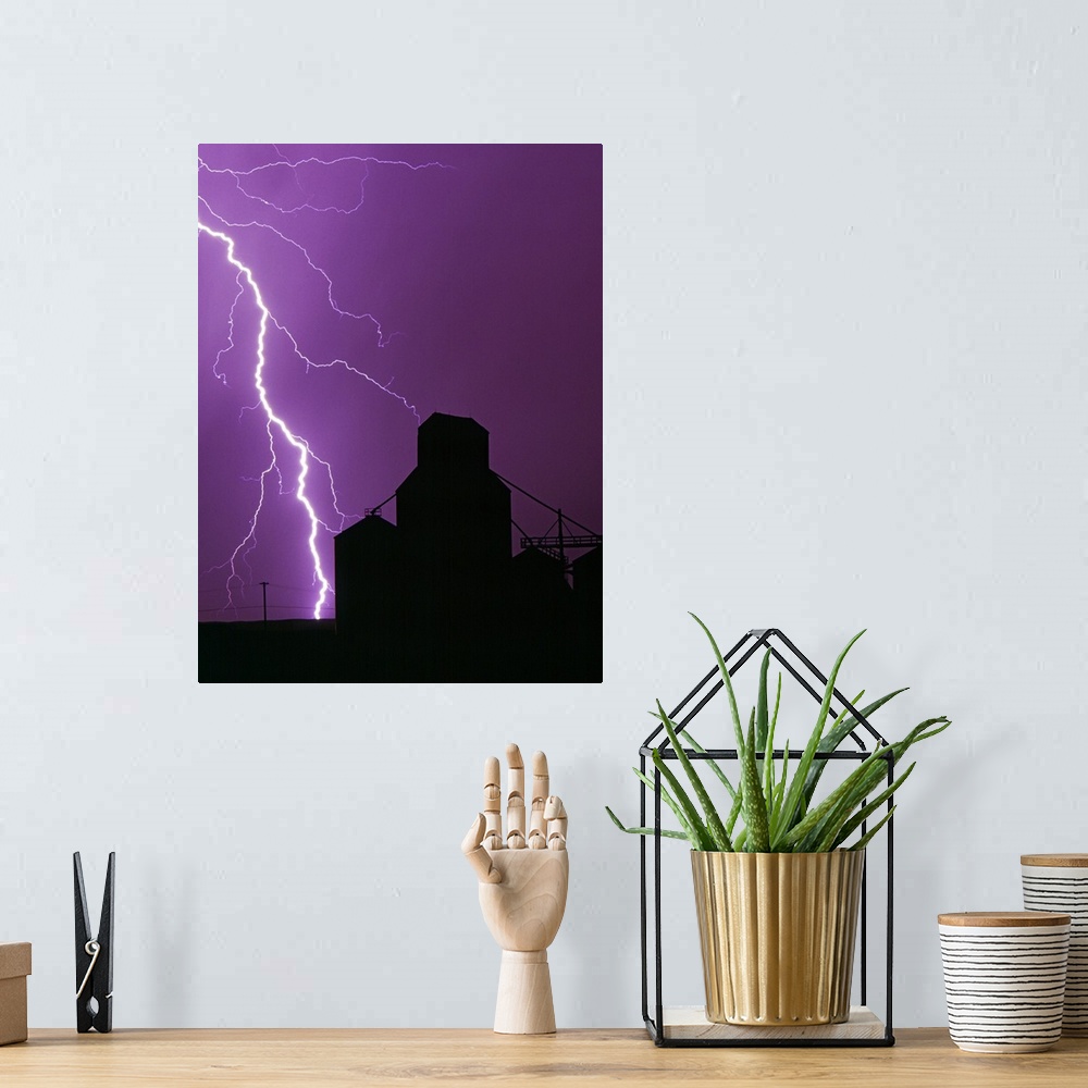 A bohemian room featuring A bolt of lightning lights up the night sky during a storm silhouetting a grain elevator